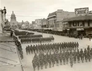 Photograph of military parade marching down Congress Avenue with Capitol in background