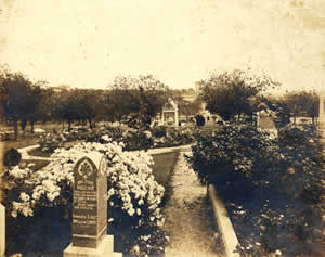 Photograph of State Cemetery with headstone of Big Foot Wallace in foreground and Albert Sidney Johnston memorial in background