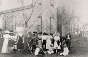 Photograph of group of people standing in front of church under construction