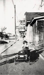 Photograph of Ellis in toy car riding on sidewalk