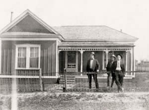Photograph of Mr. Thorp and two friends standing in the yard of one-story house