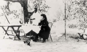 Photograph of Mrs. Ney seated at a table with a servant standing beside her