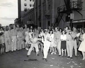 Photograph of Service men and civilians celebrating V.J. Day downtown