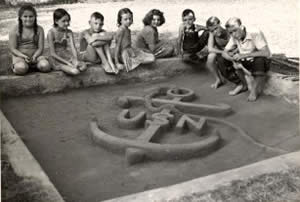 Photograph of children posed behind sand sculpture