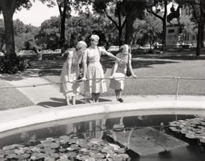 Photograph of three uniformed women standing around pond