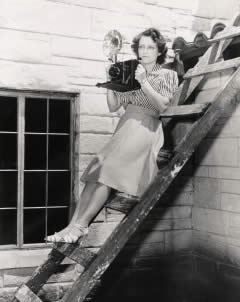 Photograph of Elnora Douglass on ladder with camera