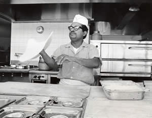 Photograph of man tossing pizza dough