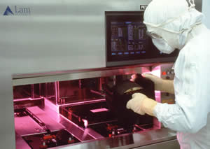 Photograph of person in clean room attire working with computer chip wafers