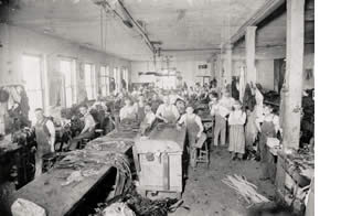 Photograph of men at tables inside leather factory